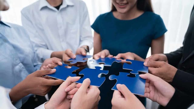 Team holding blue puzzle pieces together.