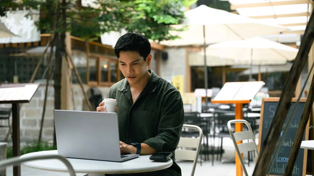 Man working on laptop in outdoor cafe