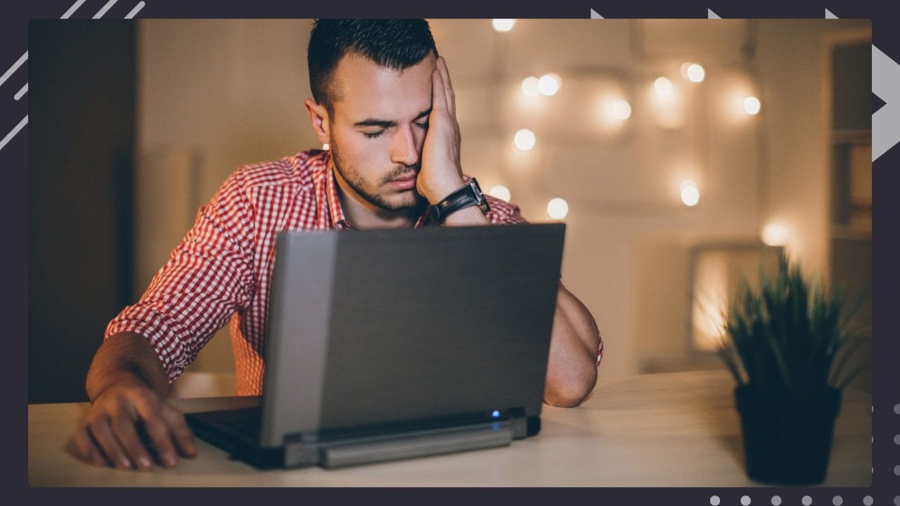 man working on laptop looking exhausted and frustrated