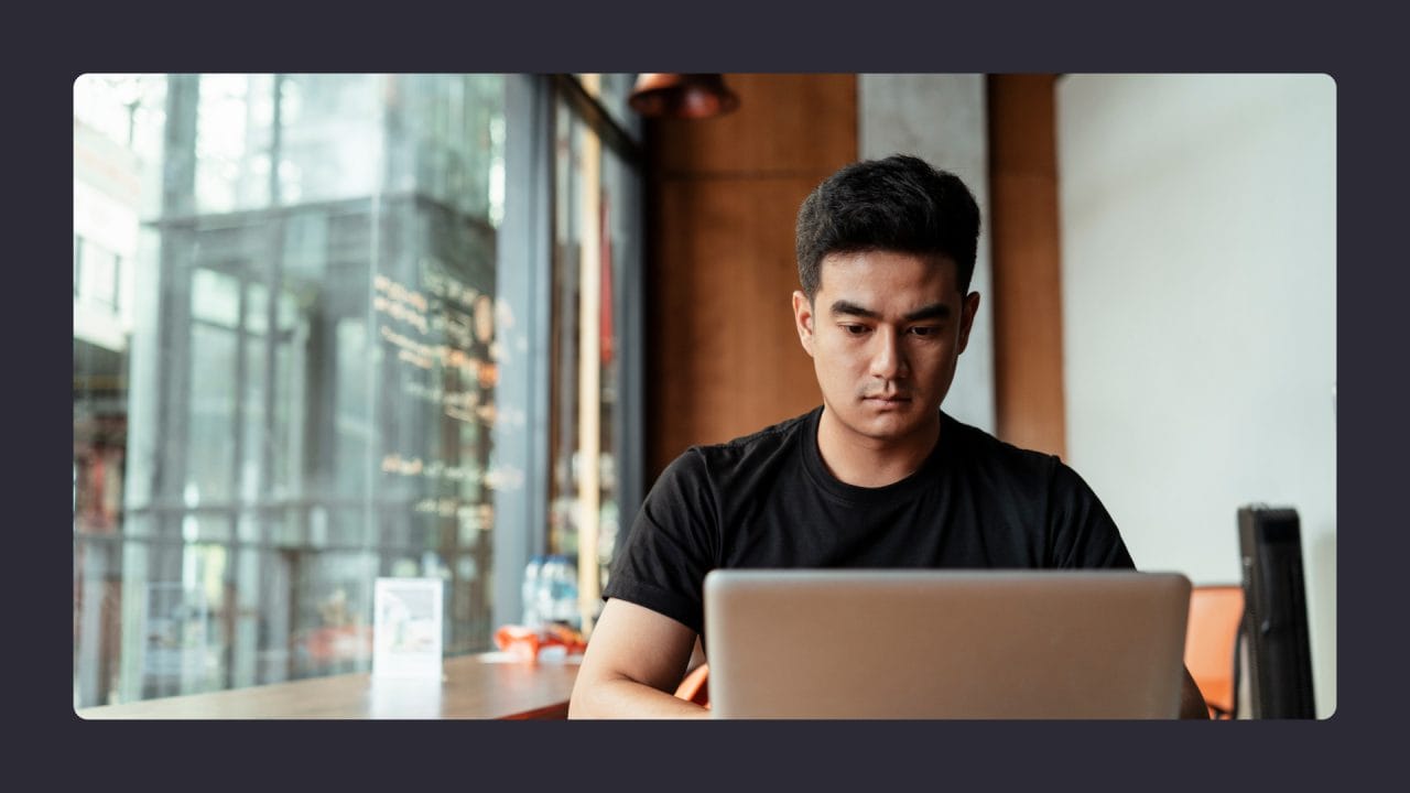 Man focused on laptop in urban café setting