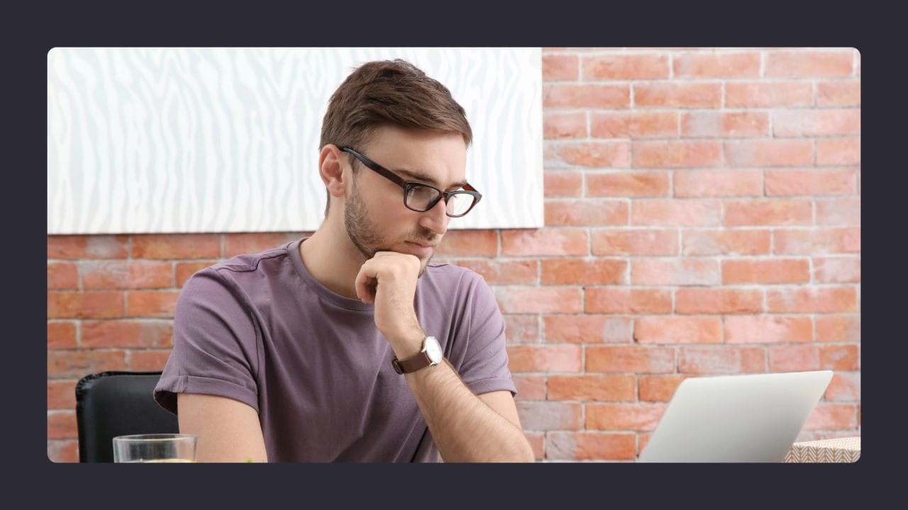 Man pondering at laptop in modern workspace