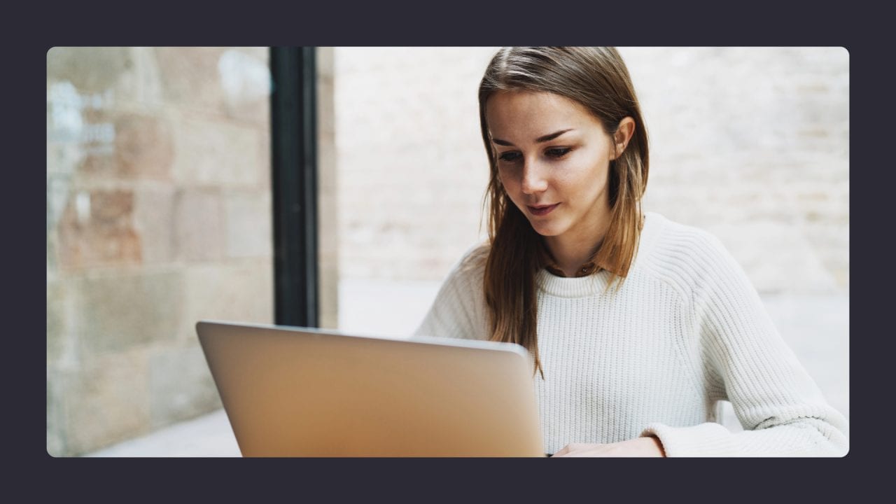 Woman working on laptop near window