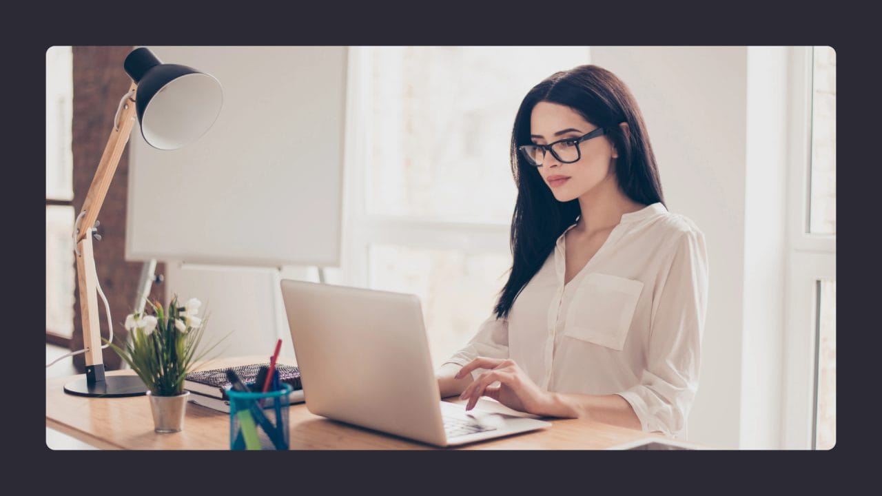 Woman in glasses using laptop at bright home office