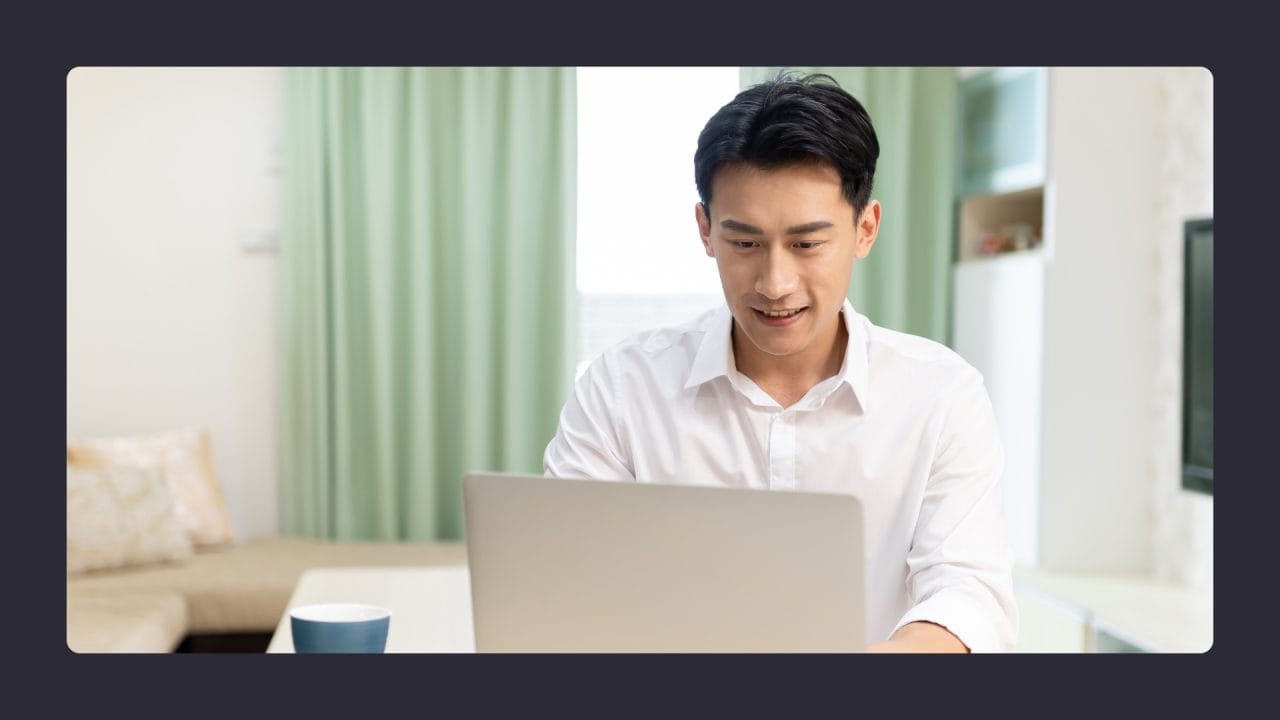 Man in white shirt using laptop at home