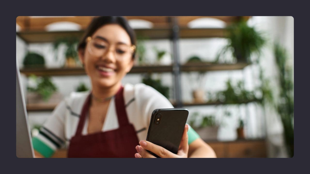 Young woman using smartphone in plant-filled kitchen