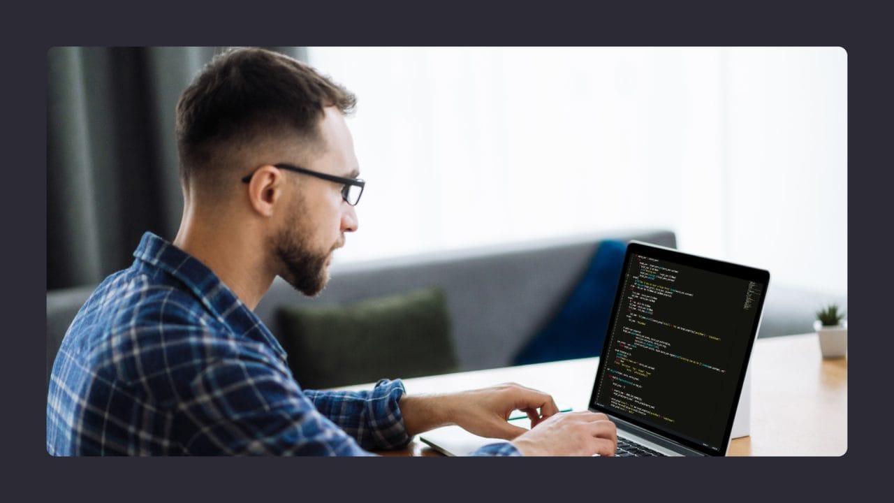 Man coding on laptop in modern office