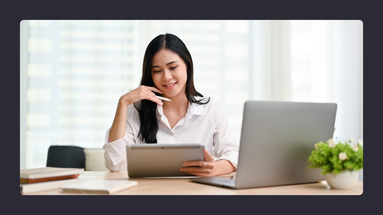 Woman using tablet and laptop at office desk