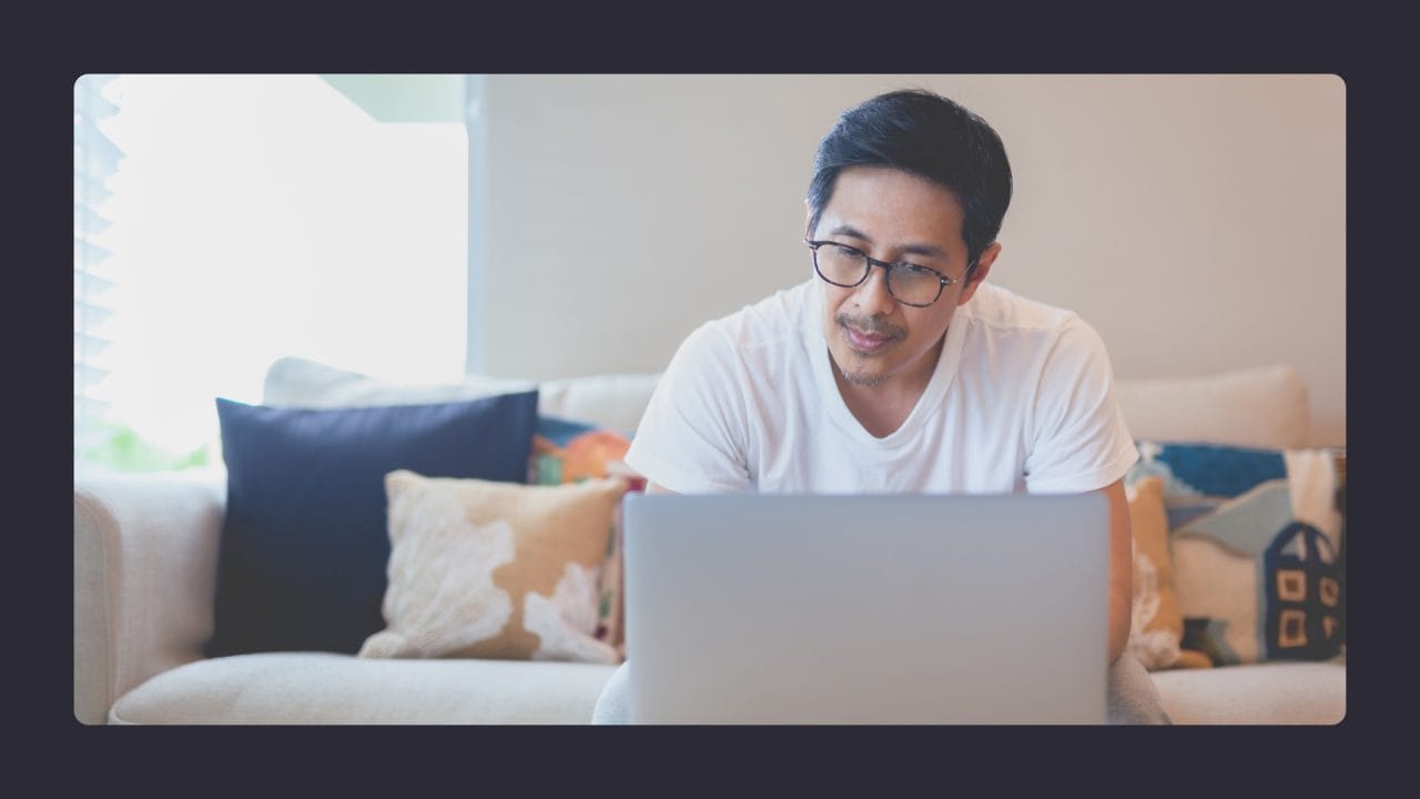 Man using laptop on sofa, cozy home environment