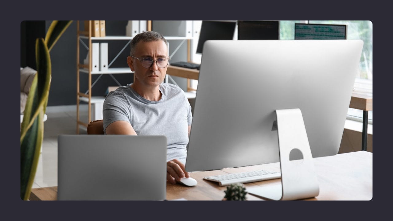 Focused man working on multiple large-screen computers