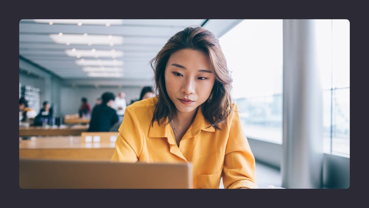 Focused woman working on laptop in busy cafe