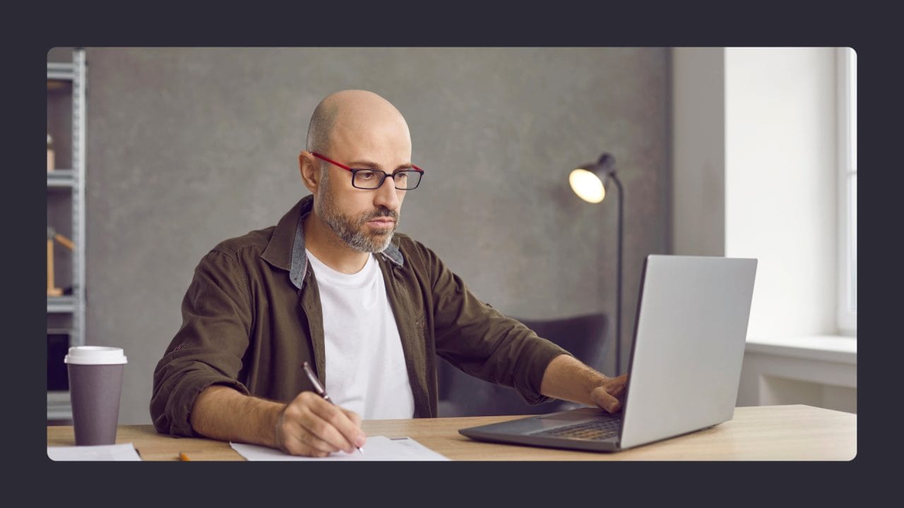 Bald man working on laptop with coffee