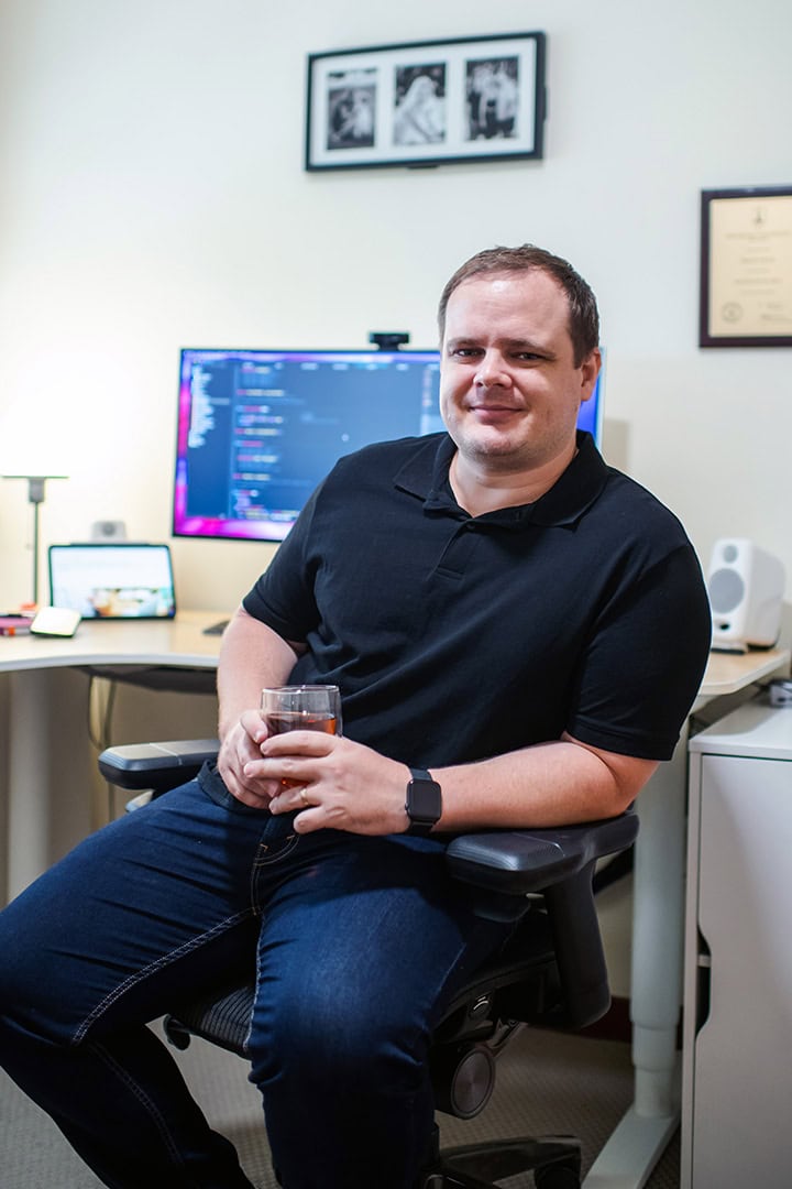 Man smiling in office with computer and photographs