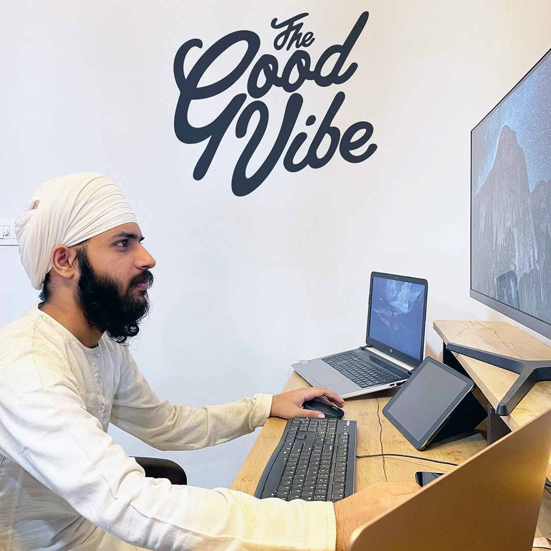 Man in turban working at multi-device desk setup