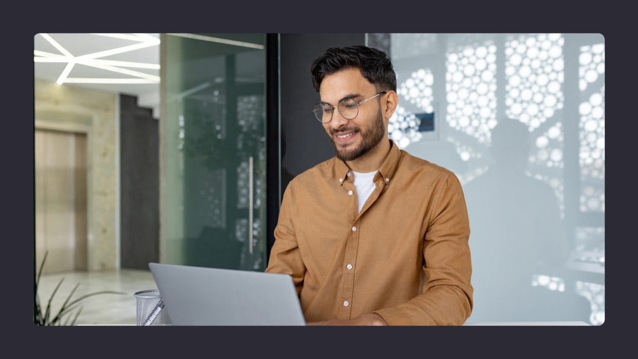 Smiling man using laptop in modern office setting