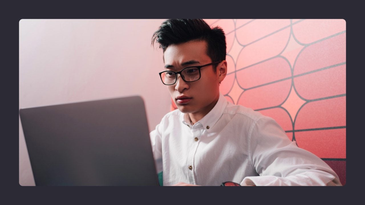 Young man with glasses using laptop intently