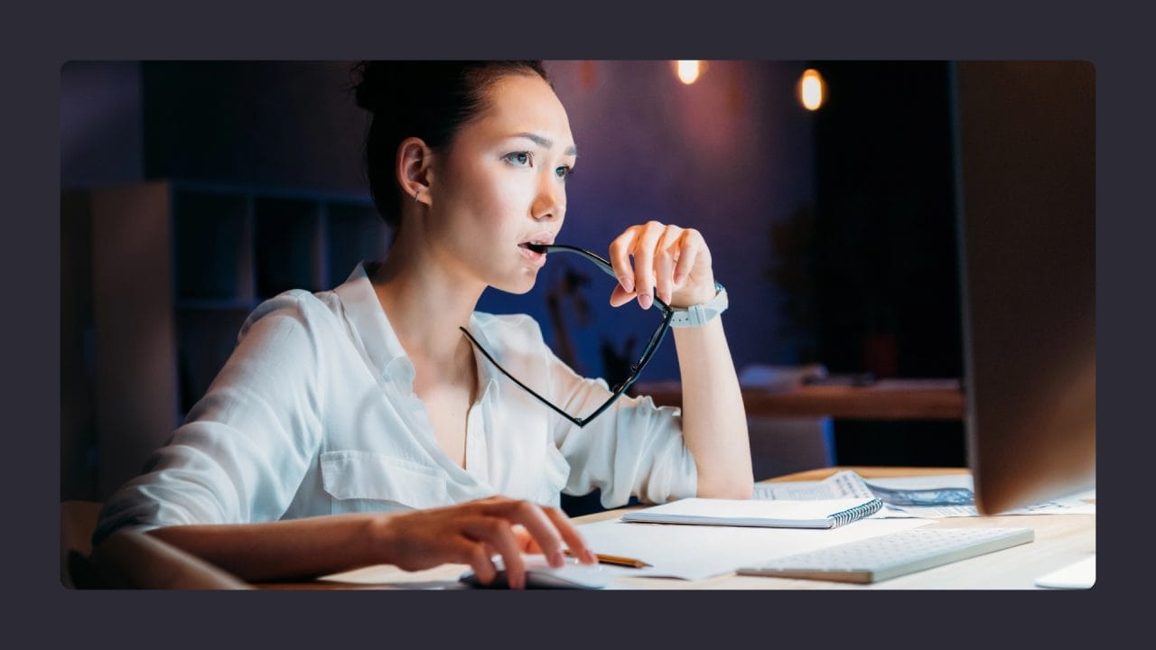 Woman working late, holding glasses, focused expression