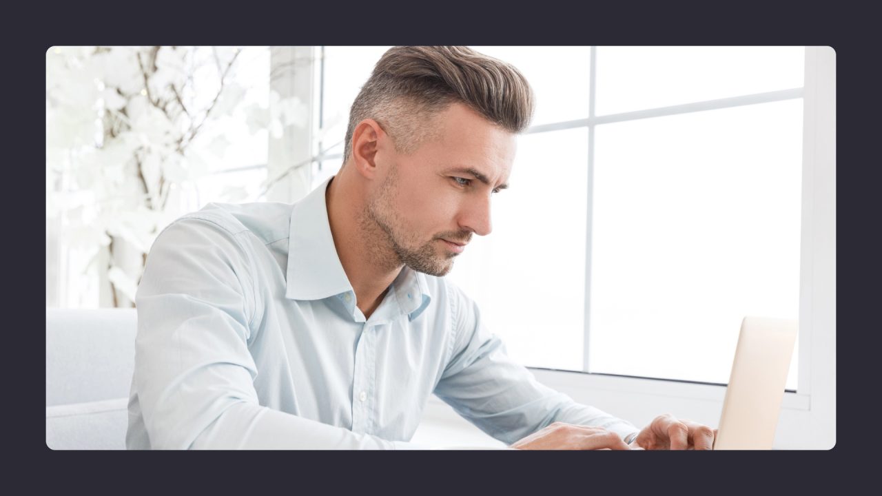 Focused man working on laptop in bright office