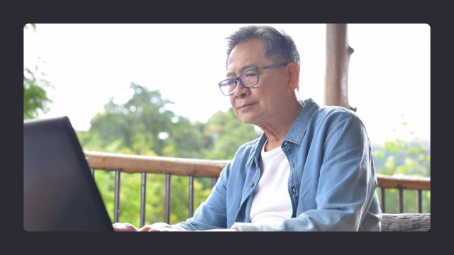 Senior man using laptop outdoors on sunny day