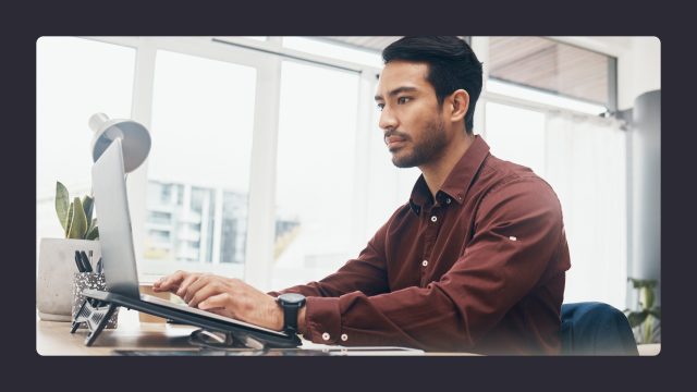 Man in maroon shirt working at office desk