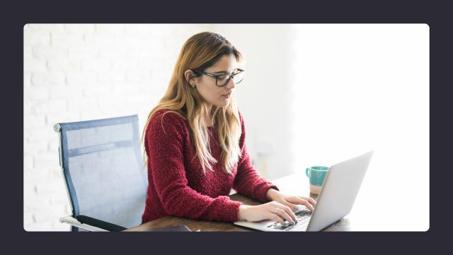 Woman in red sweater working on laptop