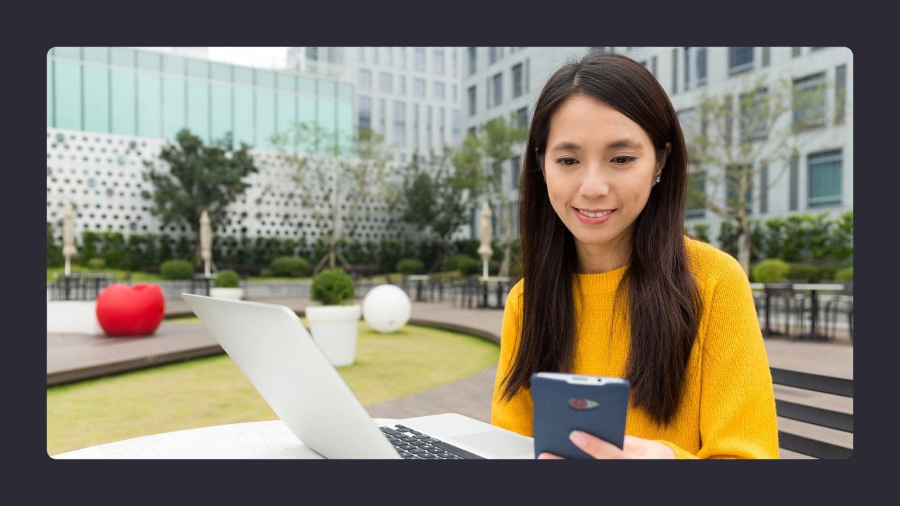 Woman using laptop and smartphone outdoors in city