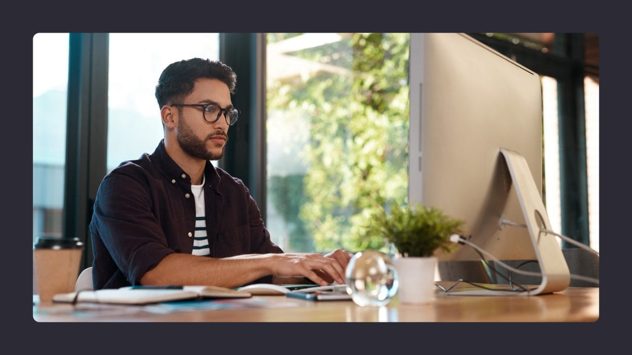 Man working intently at computer in sunlit office