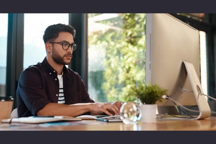 Man working intently at computer in sunlit office