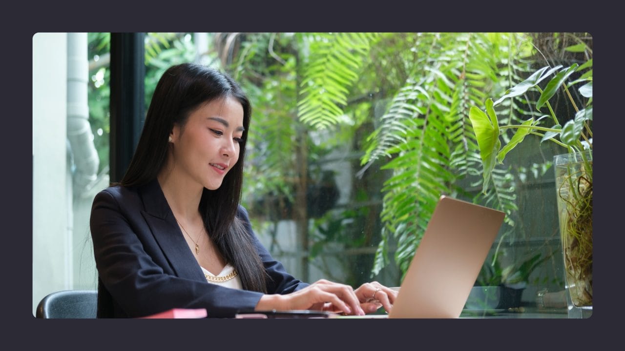 Woman working on laptop in lush indoor setting