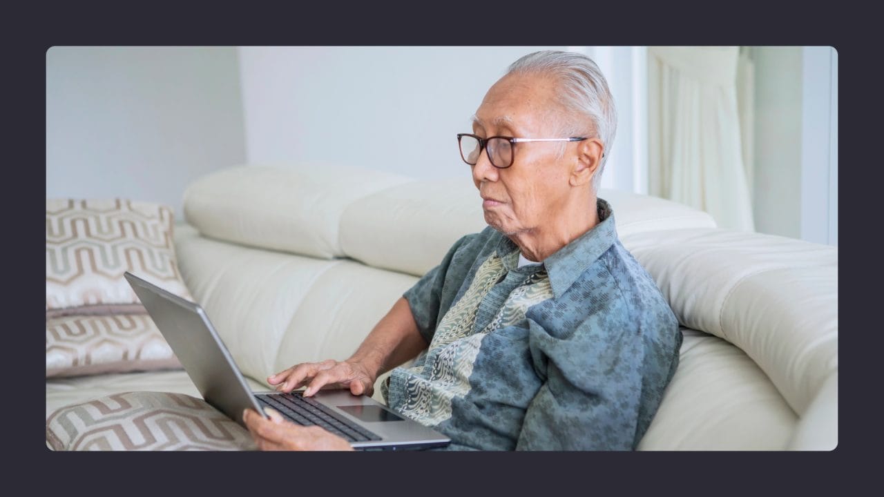 Elderly man using laptop on couch at home